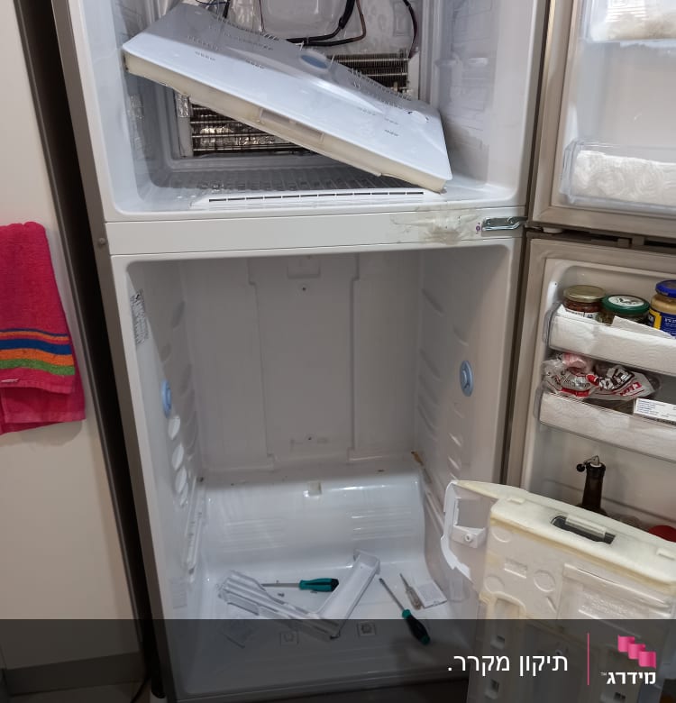 מקרר פתוח עם כלים לתיקון וחלקים מפורקים